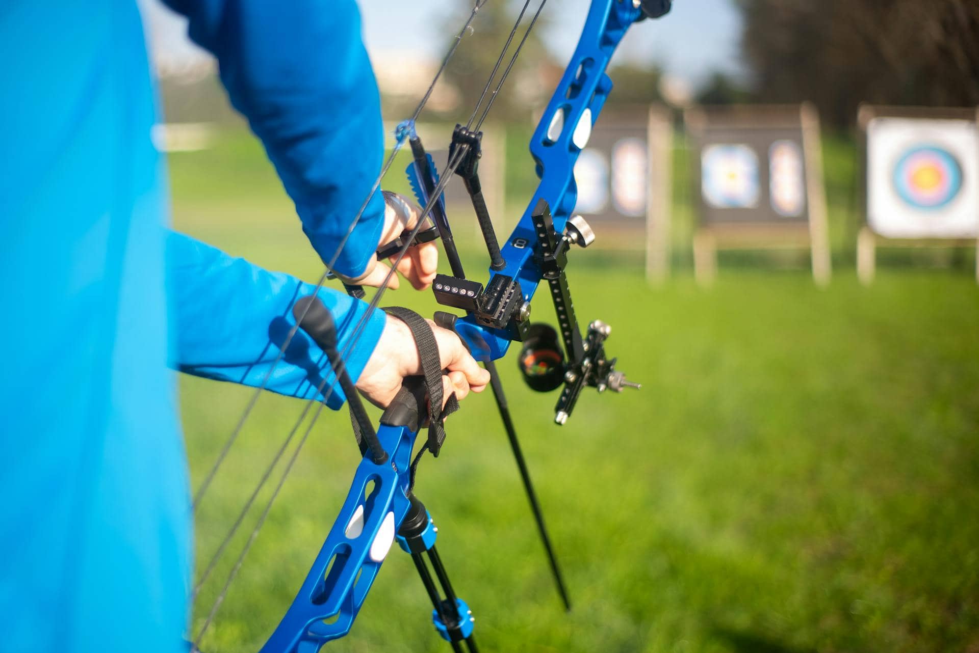 An archer holding a compound bow with a bow sight